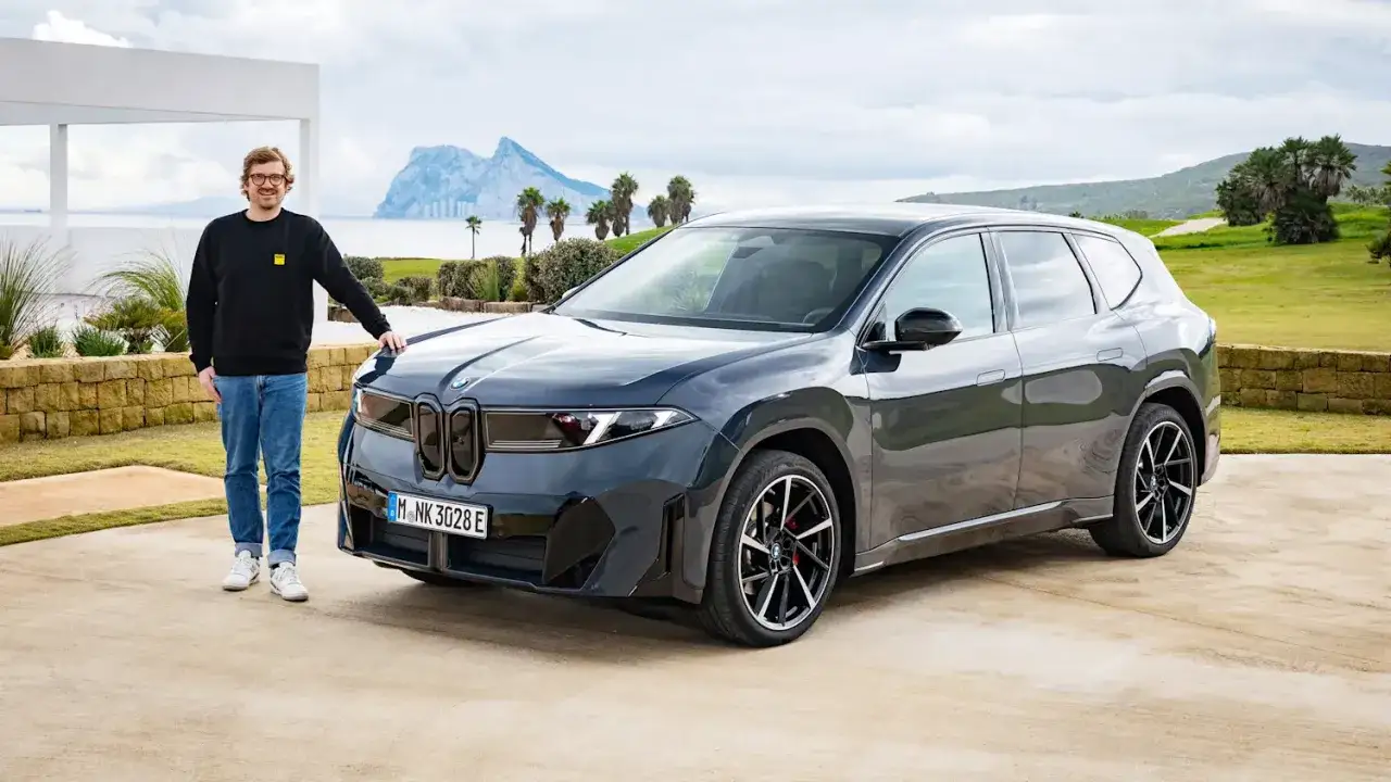 Mann neben BMW iX3. Ein Reichweite Test mit dem Elektro-SUV vor malerischer Küstenkulisse.