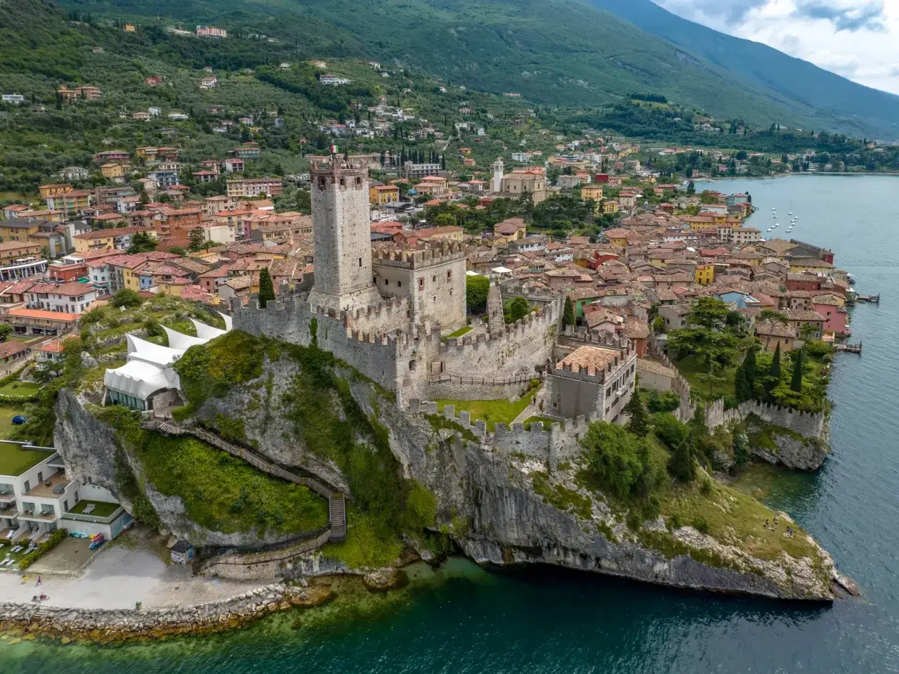 Il castello di Malcesine domina il lago, con le sue mura antiche e la torre che si stagliano contro il verde delle colline e l'azzurro dell'acqua.