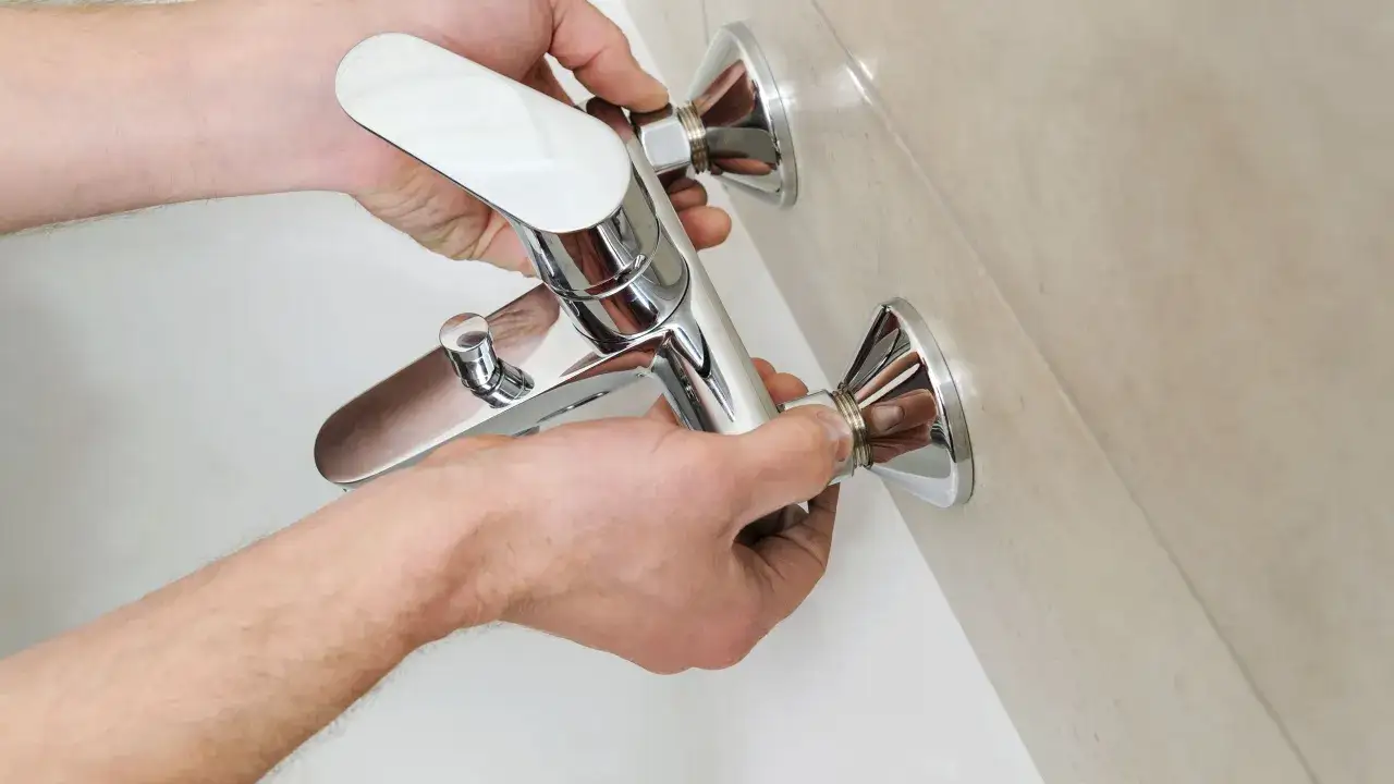 Mani che installano un rubinetto cromato per vasca da bagno. La corretta posizione del rubinetto vasca da bagno &egrave; fondamentale per un facile utilizzo.