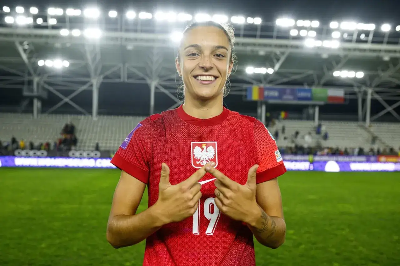 Uśmiechnięta Natalia Padilla Bidas w czerwonej koszulce z orłem, numerem 19, na tle stadionu.