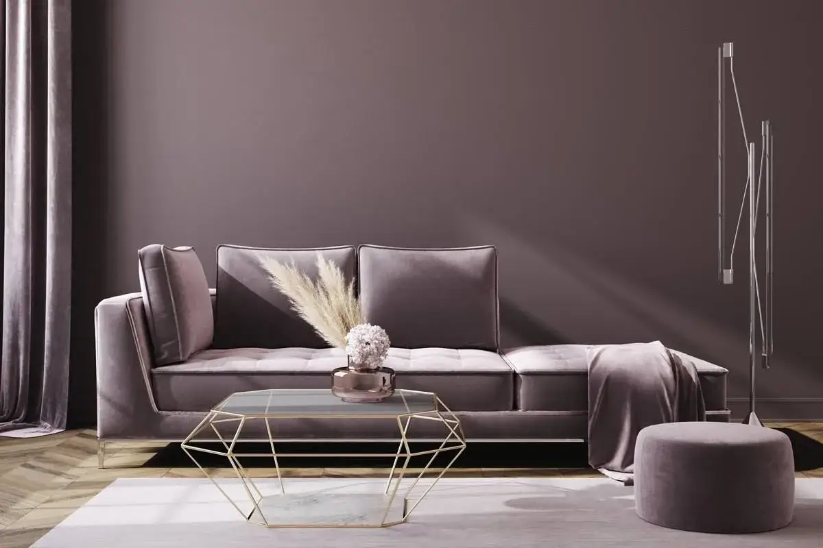 Ein stilvolles Wohnzimmer mit einem graubraunen Sofa, einem geometrischen Couchtisch und einem Hocker. Die Wandfarbe erinnert an eine **farben selber mischen tabelle** f&uuml;r dezente T&ouml;ne.