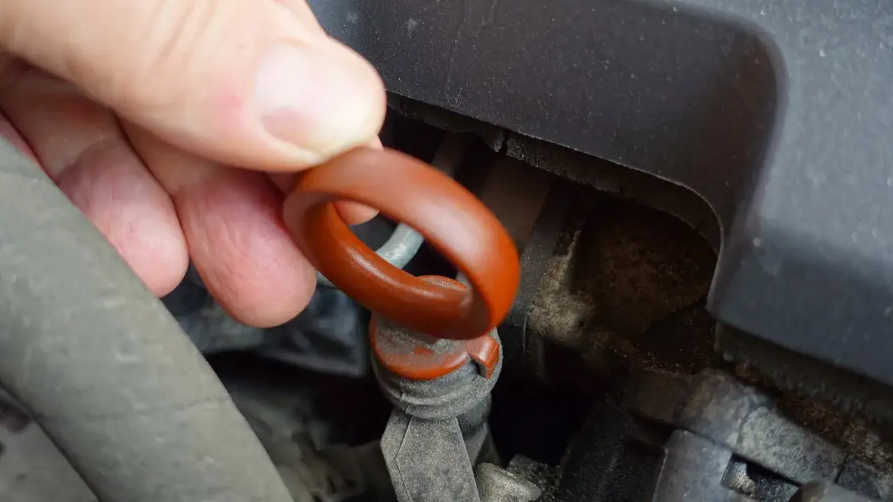 En hand drar i oljestickan f&ouml;r att kolla olja bil.