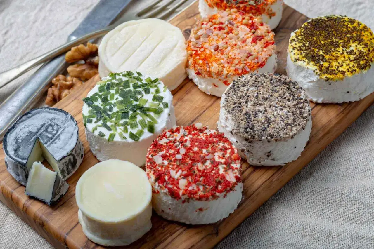 Varietà di formaggi freschi e stagionati, alcuni ricoperti di erbe e spezie. Ideali per chi cerca che formaggi si possono mangiare con il colesterolo alto.