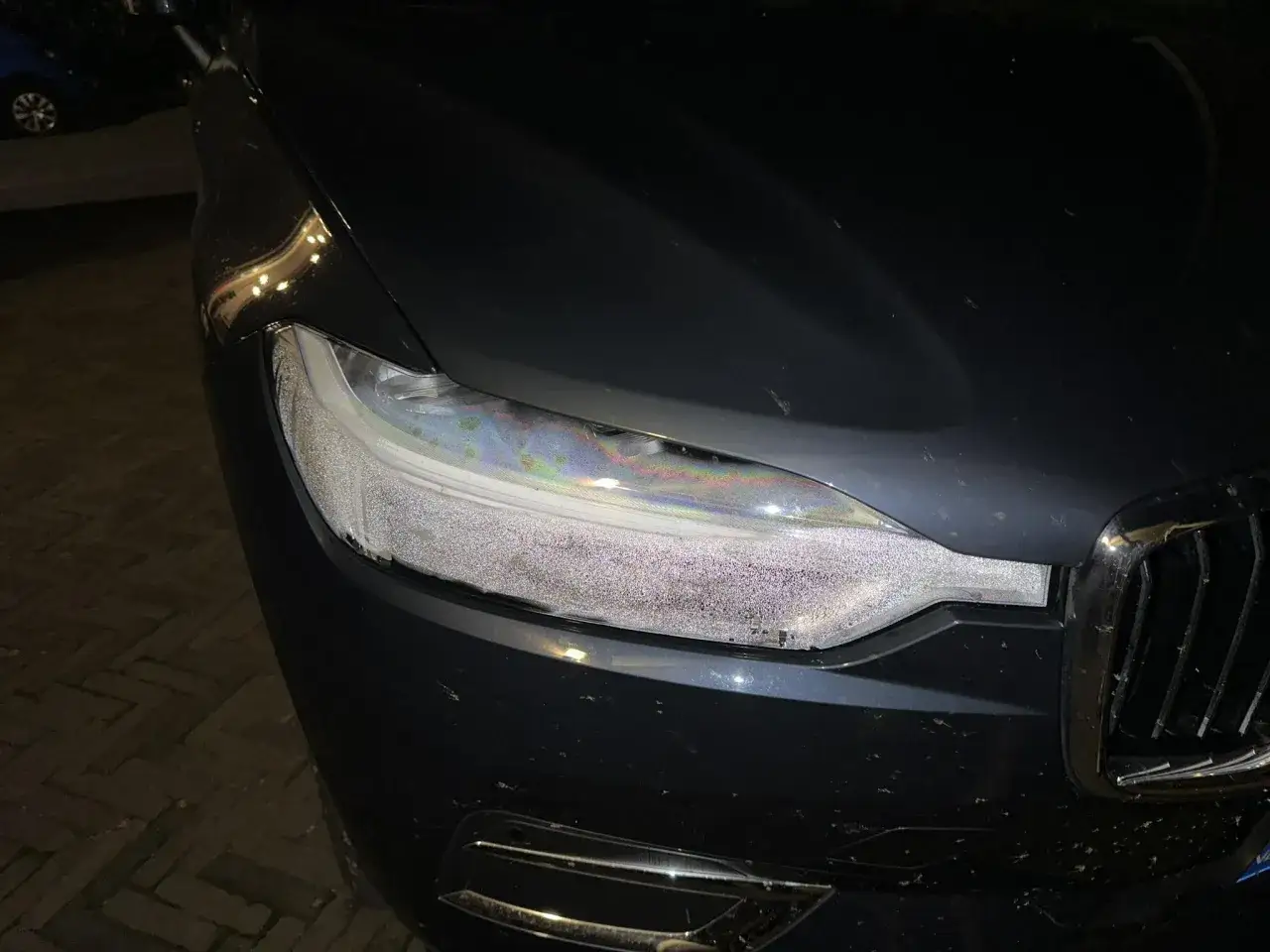 En bil med dimmiga strålkastare som reflekterar ljus från omgivningen.