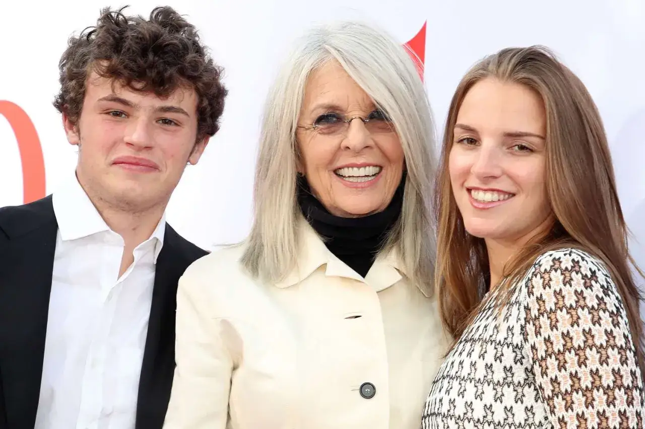 Diane Keaton z dumą prezentuje swoje dzieci, syna i córkę, uśmiechając się do obiektywu.