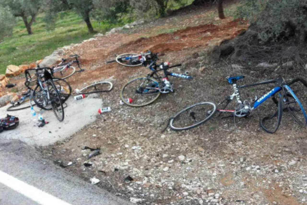 Meerdere racefietsen liggen verspreid op de grond na een ongeluk. Een fietser is waarschijnlijk gevallen, met de fietsen als stille getuigen.