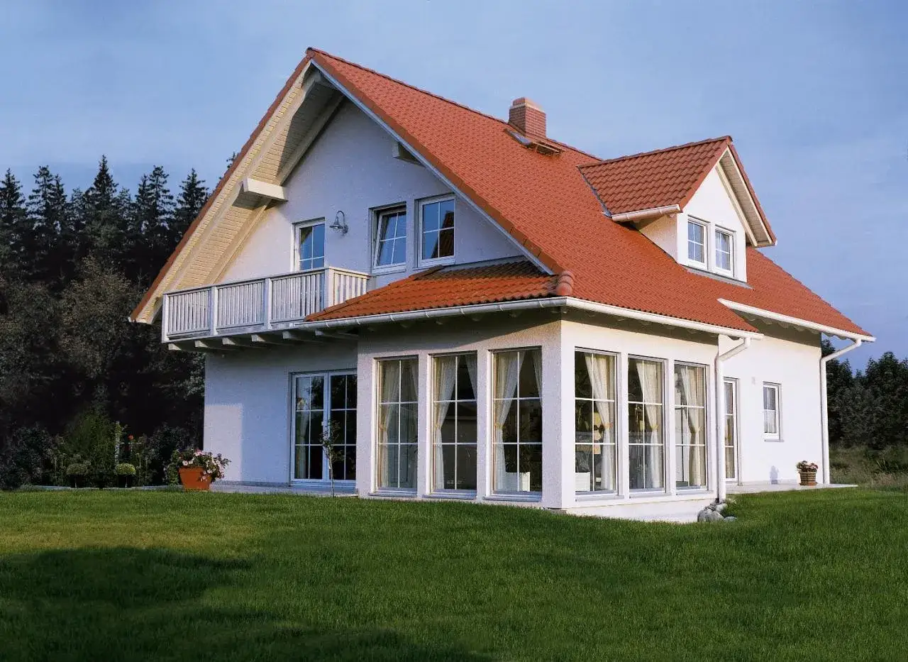 Nowoczesny dom z rozbudową w bok, projekty uwzględniające przestronne okna i balkon.