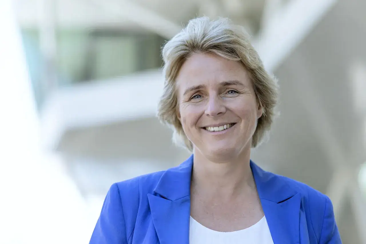 Melanie Wolfers l&auml;chelt freundlich in die Kamera, tr&auml;gt einen blauen Blazer und hat blonde Haare.