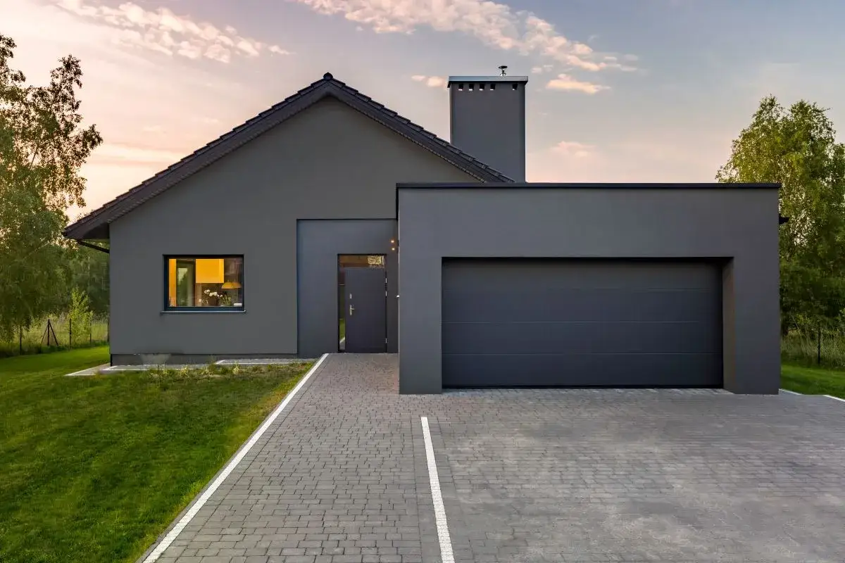 Casa moderna con tetto spiovente e garage, pronta per pitturare muro esterno grezzo.