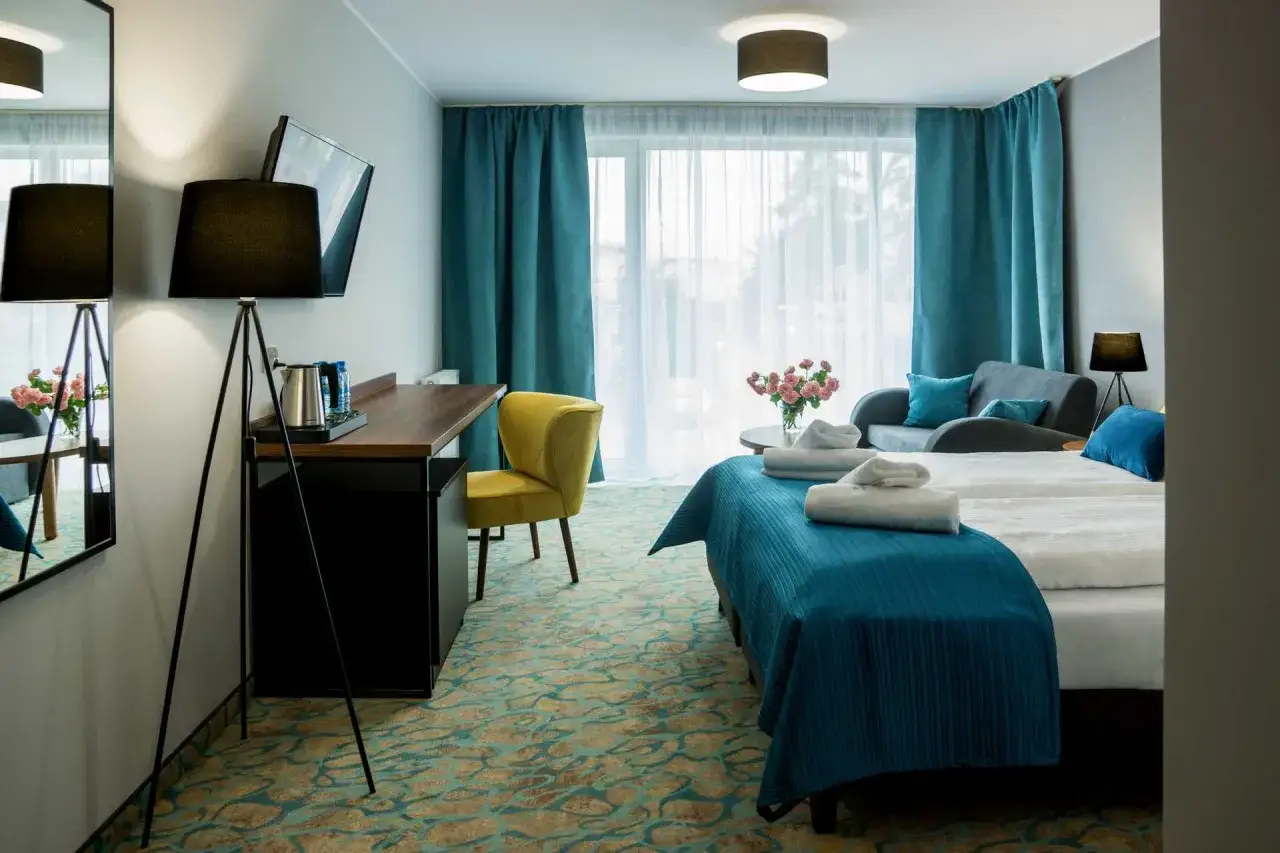 Przytulny pokój hotelowy z dwoma łóżkami, kanapą i biurkiem. Wiele osób szuka stella resort & spa opinie, by sprawdzić komfort.