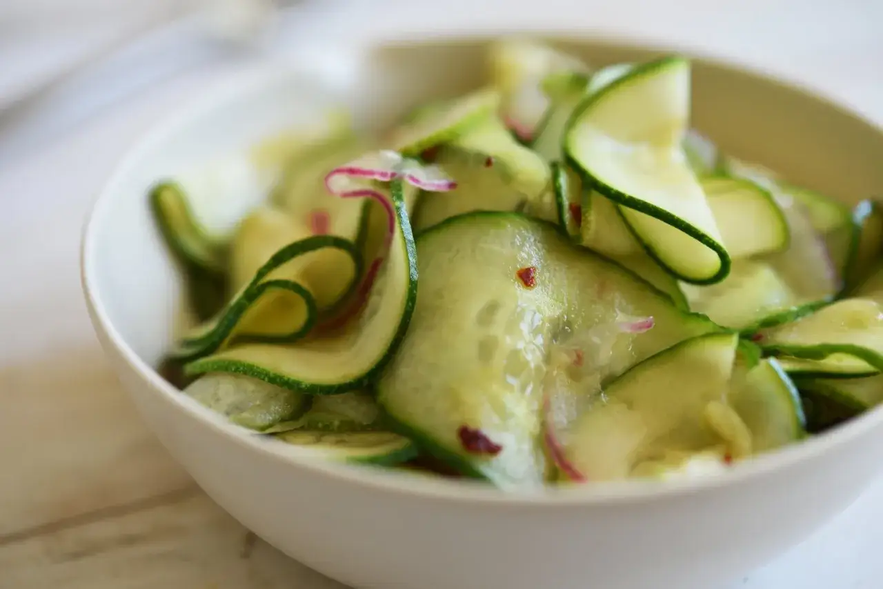 En skål med krispig gurka sallad, tunt skivad med inslag av rödlök och chili. Perfekt som tillbehör.