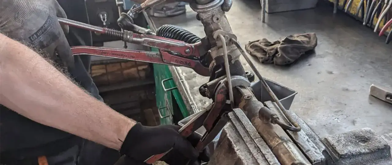 Mechanik pracuje nad regeneracją przekładni kierowniczych, używając narzędzi do demontażu.