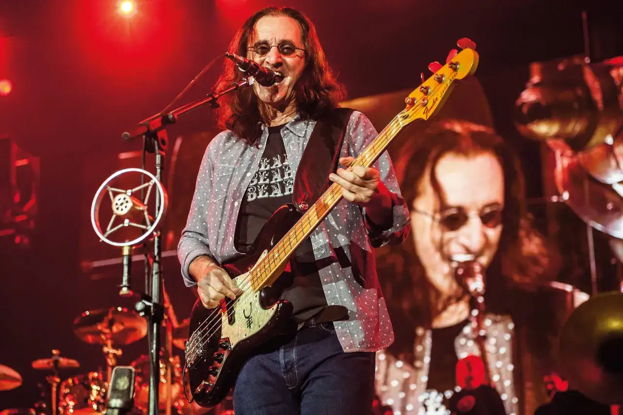 Geddy Lee, der beste Bassist der Welt, spielt auf der Bühne mit seiner Fender Jazz Bass. Rote Lichter beleuchten die Szene.