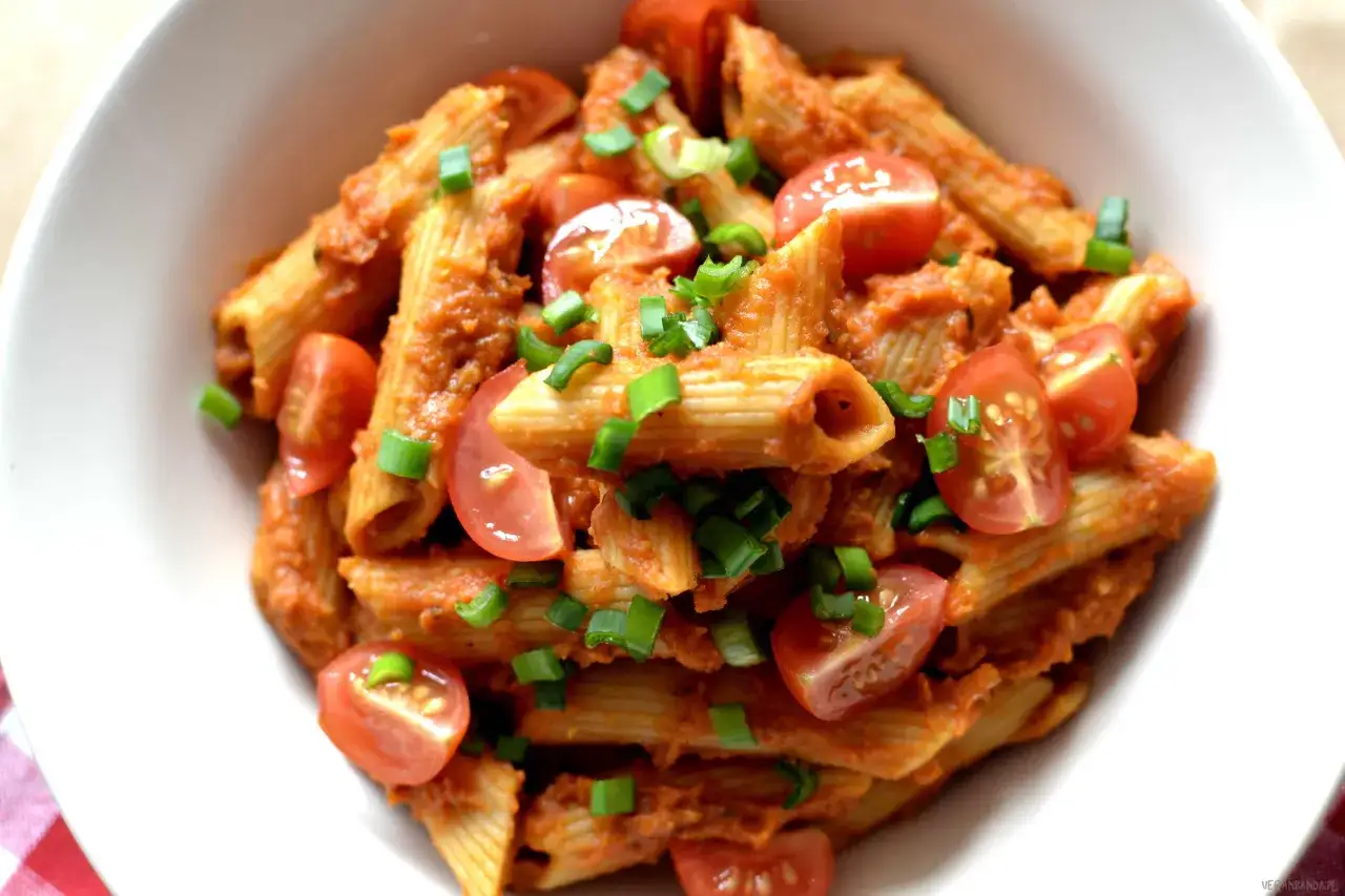 Penne pełnoziarniste w sosie pomidorowym, ozdobione pomidorkami koktajlowymi i szczypiorkiem. Wygląda jak mała biedronka na talerzu!
