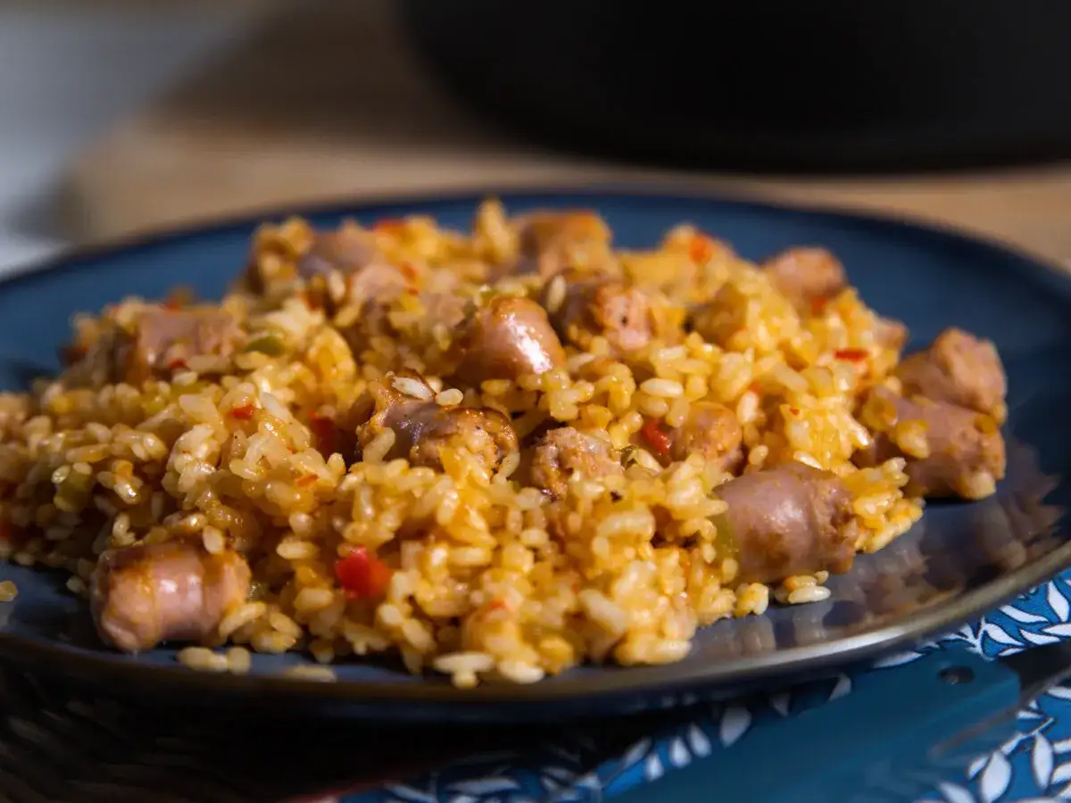 Un plato de arroz con salchichas, pimientos y especias, listo para disfrutar.