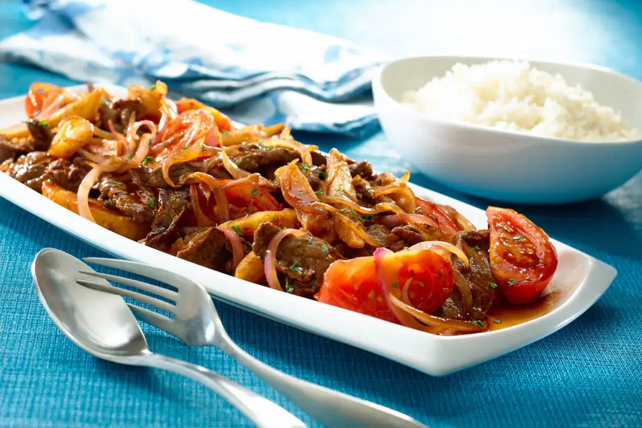 Lomo saltado, un plato peruano con carne, cebolla, tomate y papas fritas, servido con arroz blanco.