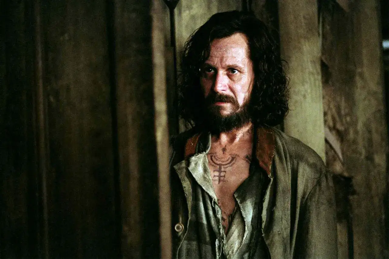 Gary Oldman jako Syriusz Black w Harry Potterze, z tatuażem na piersi, wygląda na zmęczonego i zamyślonego.
