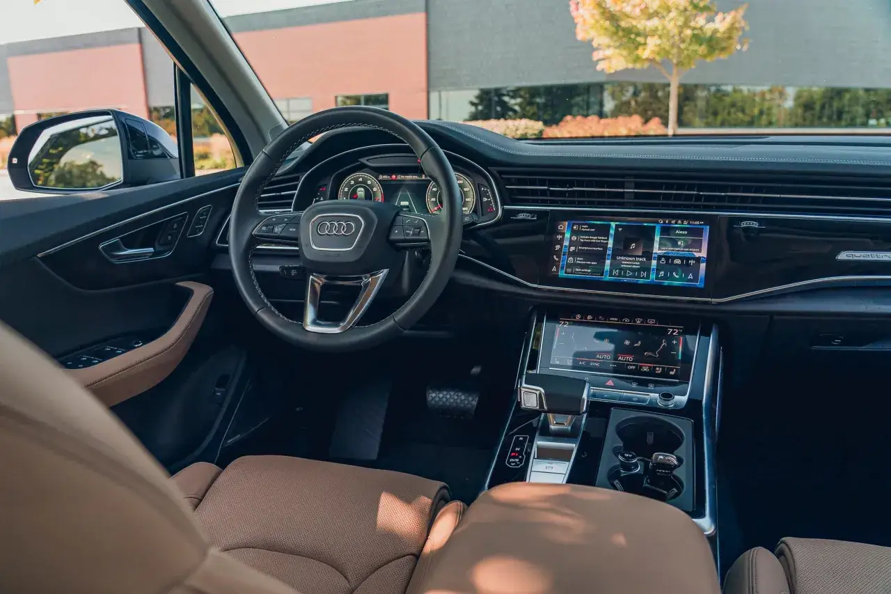 Wnętrze Audi Q7 z beżową tapicerką i nowoczesnym panelem sterowania. Sprawdź aktualną audi q7 cena.