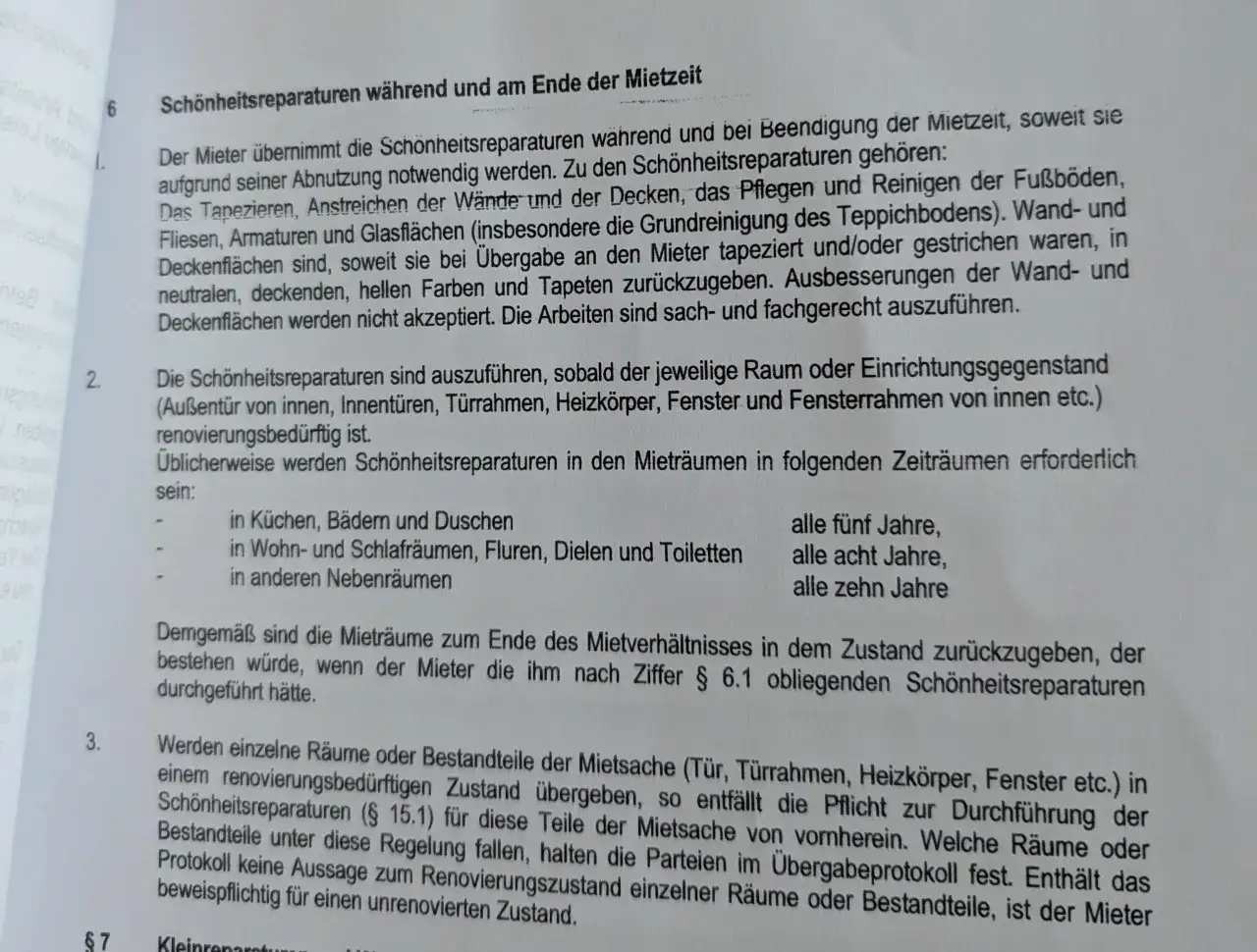 Textauszug aus einem Mietvertrag, der Schönheitsreparaturen bei Auszug regelt. Details zu Malerarbeiten, Tapezieren und Fristen.