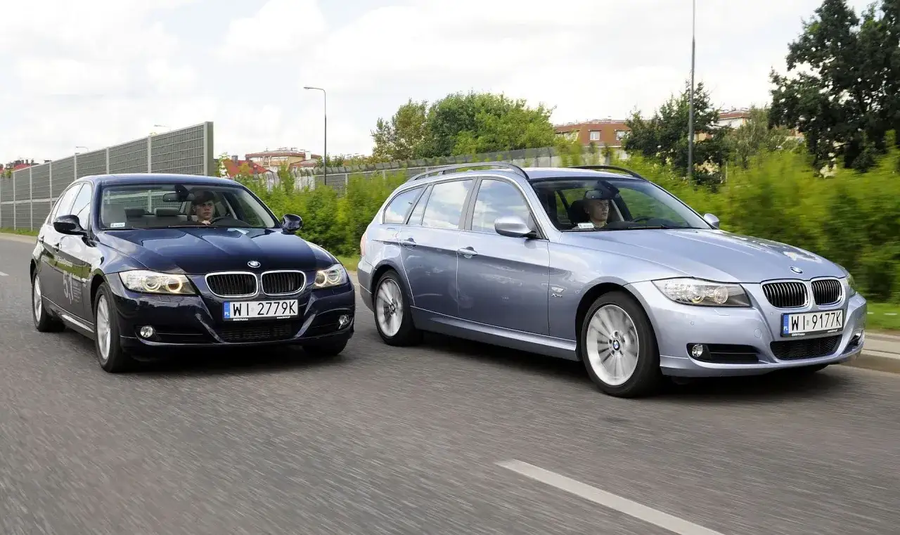 Dwa BMW E90 2.0 benzyna jadące obok siebie po drodze. Jeden to ciemny sedan, drugi to jasny kombi.