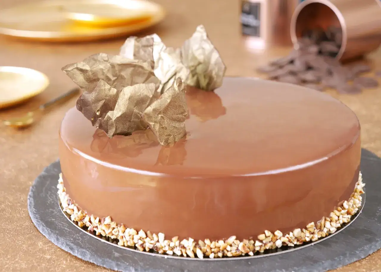 Gâteau glacé au caramel, décoré de pépites dorées et de noisettes concassées. Un insert caramel facile pour une touche gourmande.