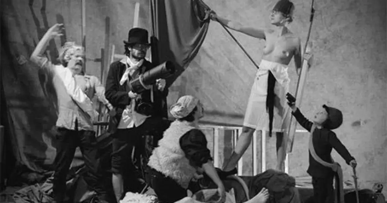 Grupa łódź kaliska w historycznych strojach, z aparatem i flagą, tworzy żywą scenę.