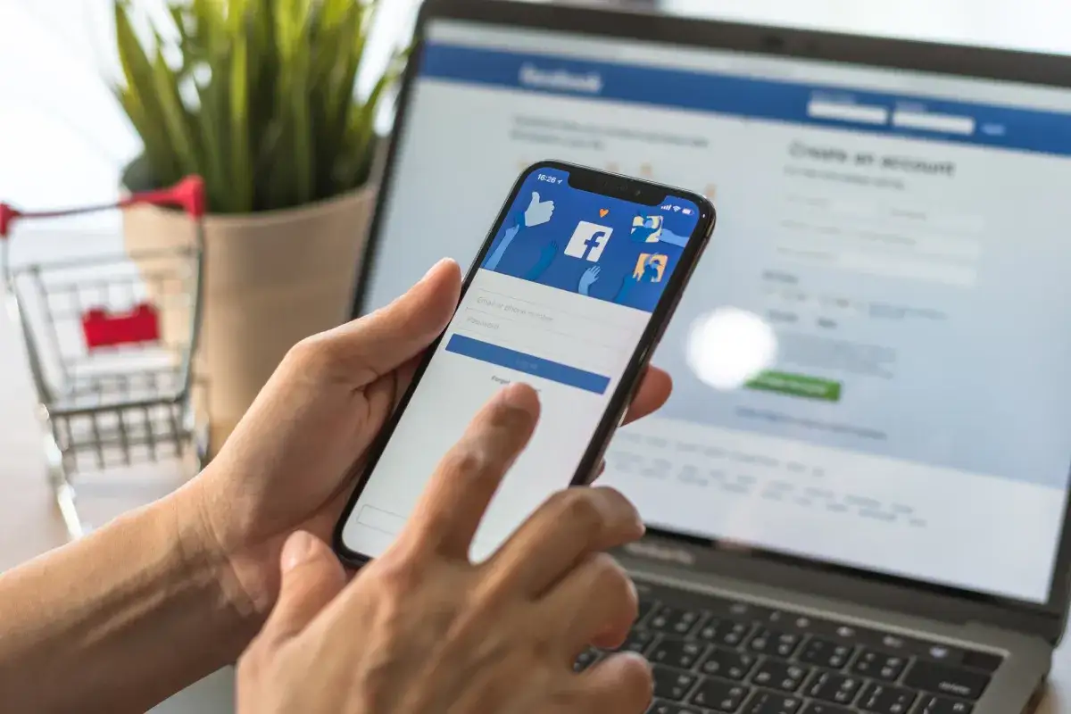 Ręce trzymające smartfon z ekranem logowania Facebooka. Dowiedz się, jak znaleźć osobę na FB po imieniu, korzystając z telefonu lub komputera.