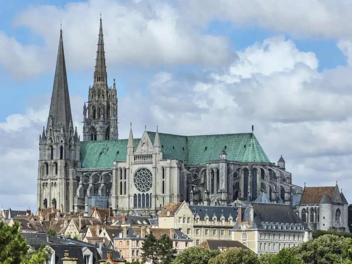 Gotycka katedra z zielonym dachem i strzelistymi wieżami, przykład wspaniałego stylu w architekturze, góruje nad miastem.