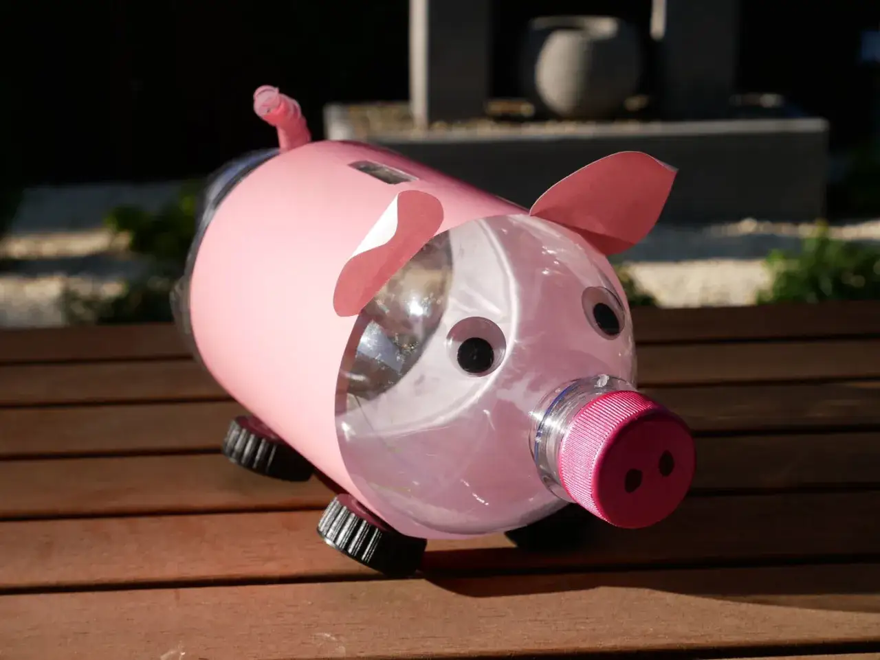 Cerdito hucha manualidades hecho con botella de pl&aacute;stico rosa, ojos saltones y tap&oacute;n rojo. &iexcl;Listo para ahorrar!
