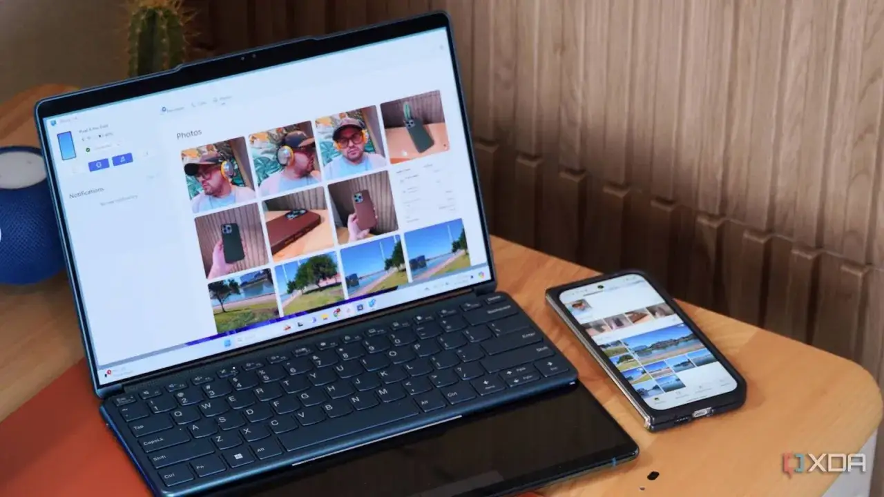 Na zdjęciu widać otwarty laptop z widokiem na zdjęcia z twojego telefonu, obok leży smartfon.