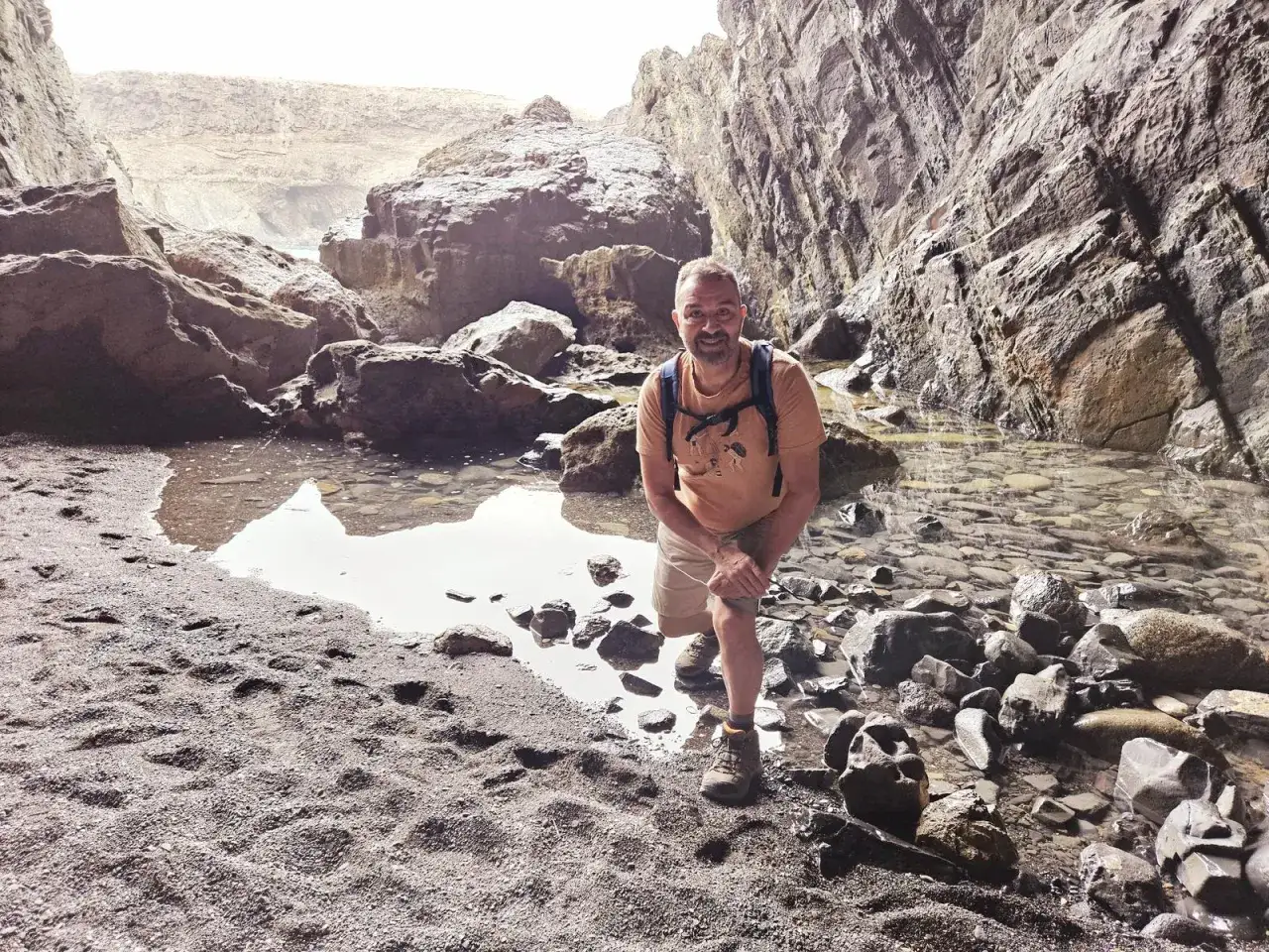 Hombre sonriente en las cuevas de Ajuy, rodeado de rocas y agua.