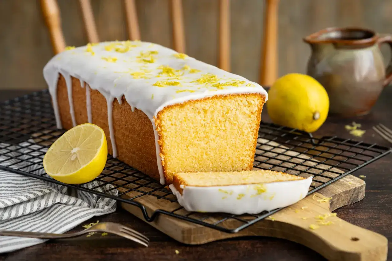 Saftiger zitronenkuchen wie bei Oma, mit Zuckerguss und frischer Zitronenschale bestreut. Ein Stück ist bereits angeschnitten.