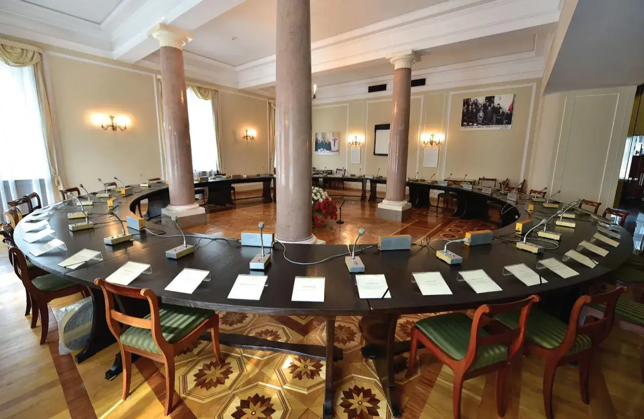 Okrągły st&oacute;ł z mikrofonami, miejsce ważnych debat nad historią polityczną Polski 1989-2023.