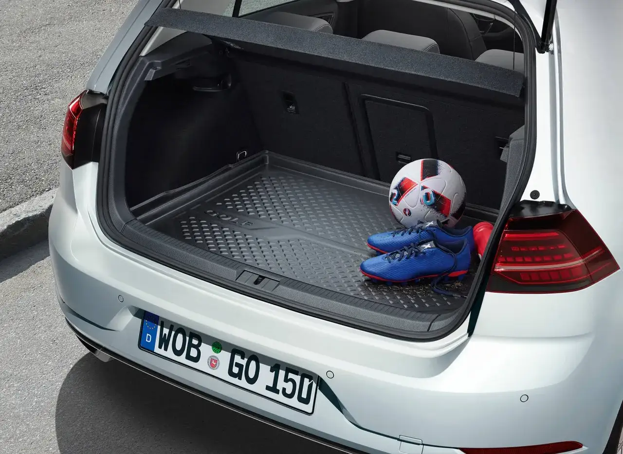 Bagażnik Volkswagena Golfa 1.4 TSI gotowy na mecz: piłka i buty piłkarskie czekają na wyjazd.