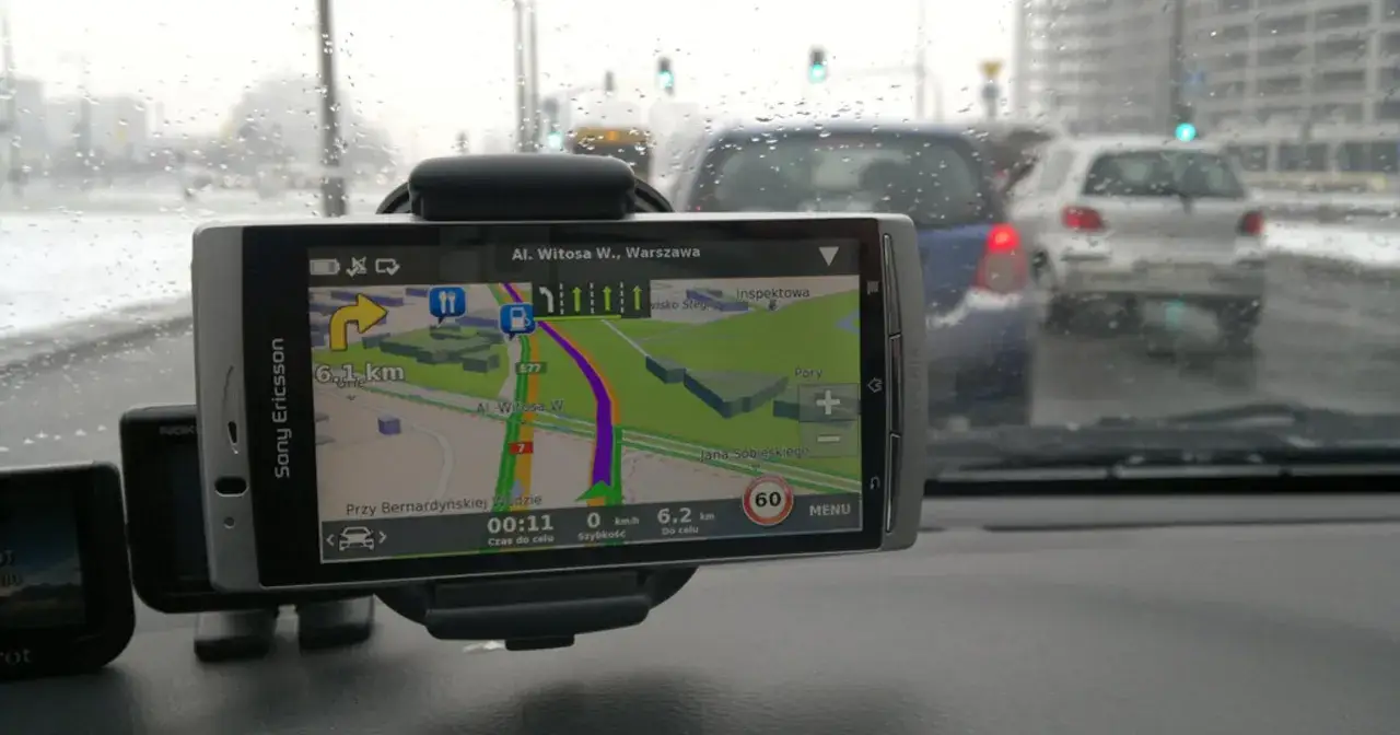 Nawigacja GPS pokazuje trasę z pominięciem dróg płatnych w deszczowy dzień w Warszawie.