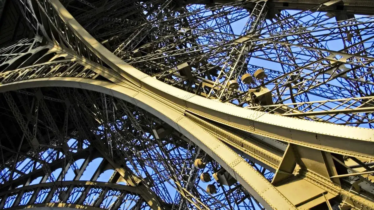 Vue en contre-plong&eacute;e de la structure m&eacute;tallique de la Tour Eiffel, un symbole de la fortune et de l'ing&eacute;niosit&eacute; de la famille Eiffel.