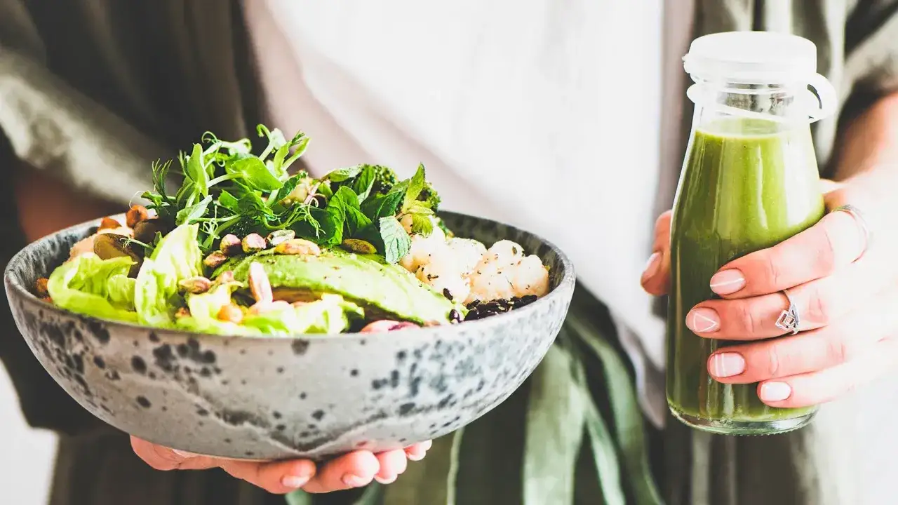 En person h&aring;ller en sk&aring;l med en n&auml;ringsrik sallad och en gr&ouml;n smoothie. Perfekt bra mat gravid f&ouml;r energi och v&auml;lm&aring;ende.