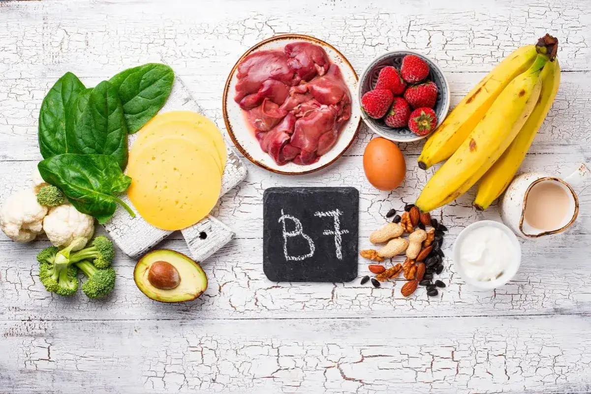 Biotyna co to? Na zdjęciu produkty bogate w witaminę B7: wątróbka, jajko, orzechy, banany, truskawki, szpinak, ser, awokado, brokuły, kalafior.