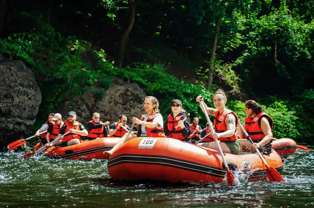 Grupa ludzi na pontonie, wiosłująca po rzece. To jest właśnie rafting – emocjonująca przygoda na wodzie!