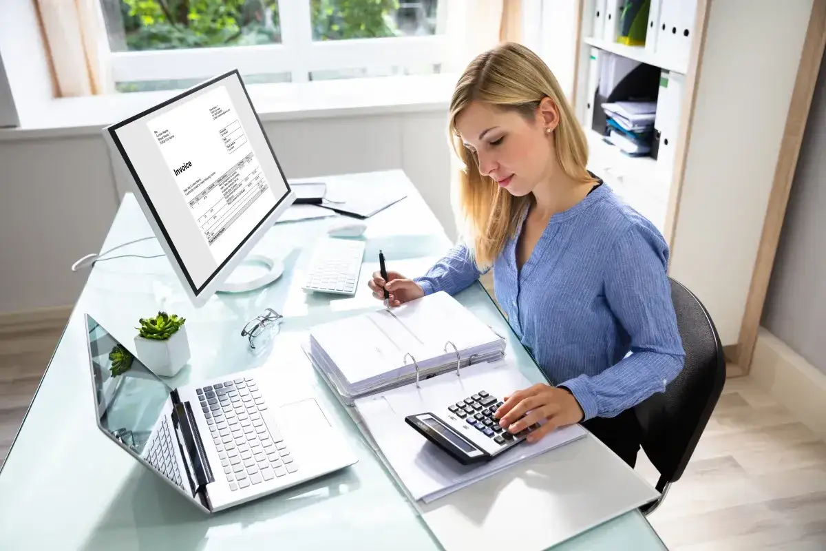 Kobieta pracuje przy biurku, analizując faktury i dane finansowe. To kluczowe dla sprawnego **e-commerce**.