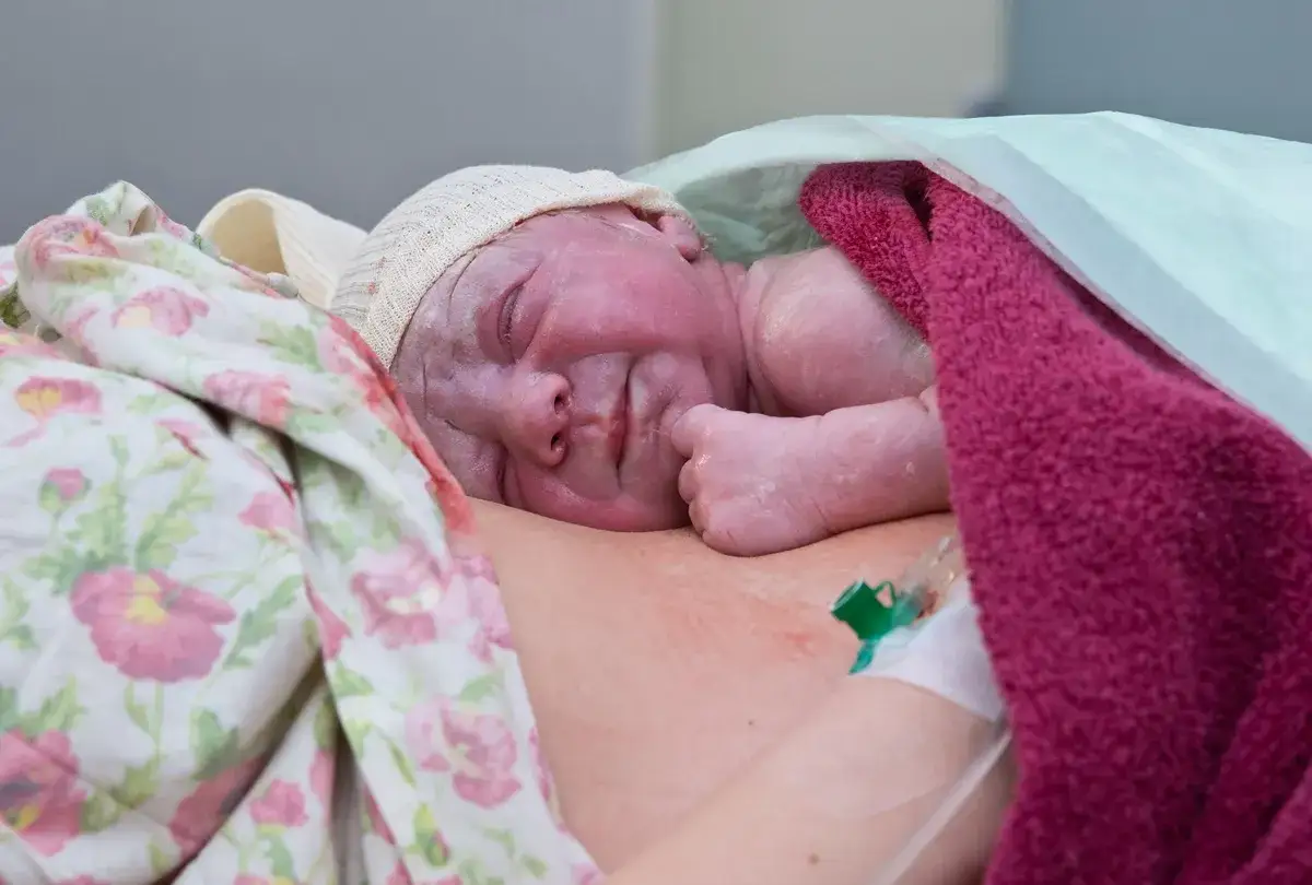 Słodki noworodek po urodzeniu, otulony kocykami, z czepkiem na głowie. Właśnie przyszedł na świat.