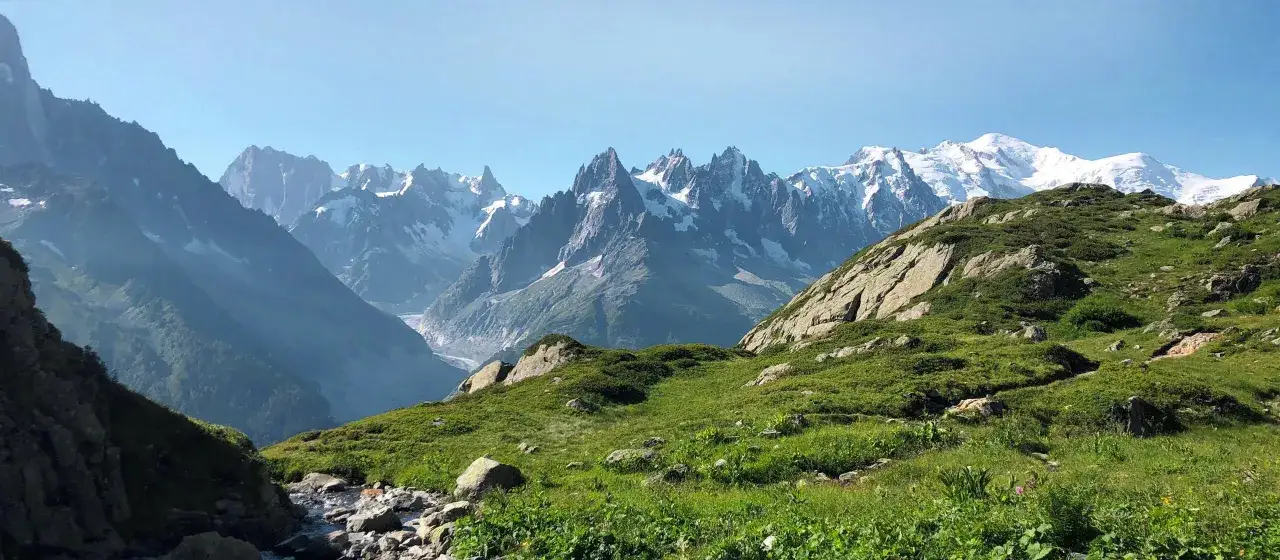 Gr&uuml;ne Almwiesen und Felsen f&uuml;hren zum majest&auml;tischen Mont Blanc.
