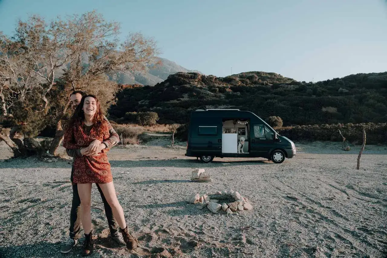 Glückliches Paar umarmt sich vor einem Campervan mit Hund, ein Highlight der Kreta-Reise.