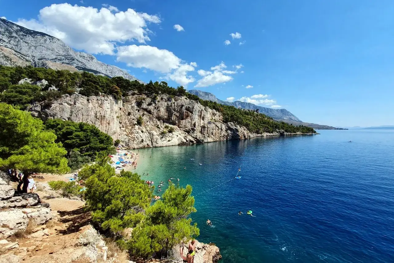 Słoneczna plaża w Makarskiej, skaliste klify, turkusowe morze i zielone sosny. Idealne miejsce na relaks i podziwianie pięknych widok&oacute;w. Makarska atrakcje zachwycają!