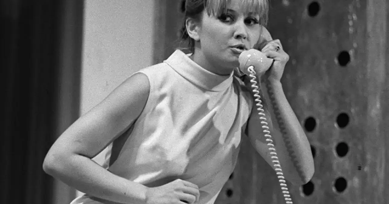 Barbara Sołtysik rozmawia przez telefon. W tle widać fragment scenografii.