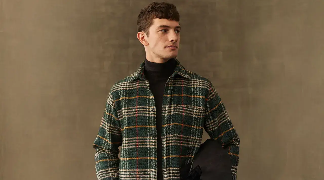 Junger Mann im l&auml;ssigen Flanellhemd-Style mit Rollkragenpullover und Jacke.