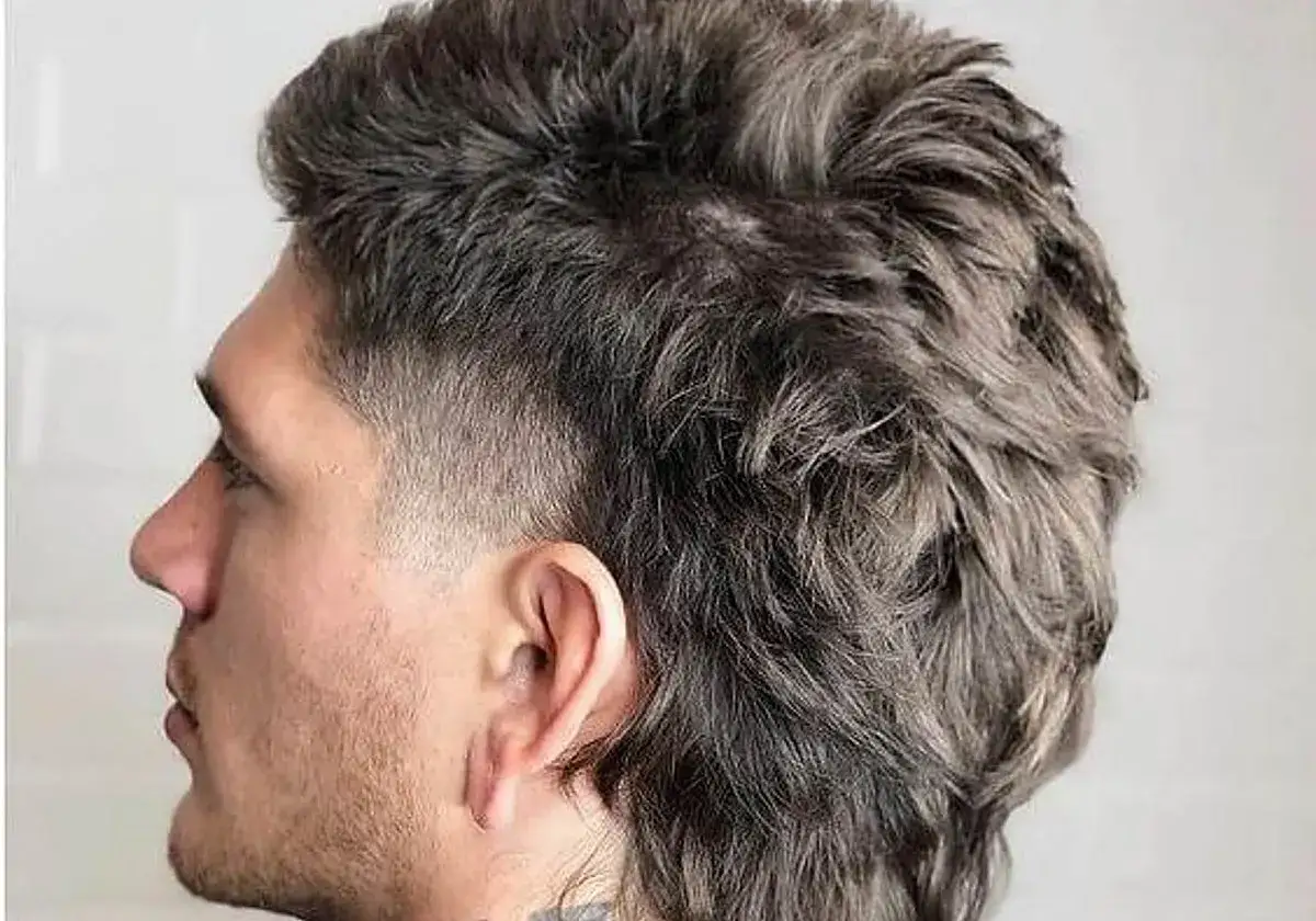 Hombre con pelo corto estilo mullet, rapado a los lados y con volumen en la parte superior y trasera.