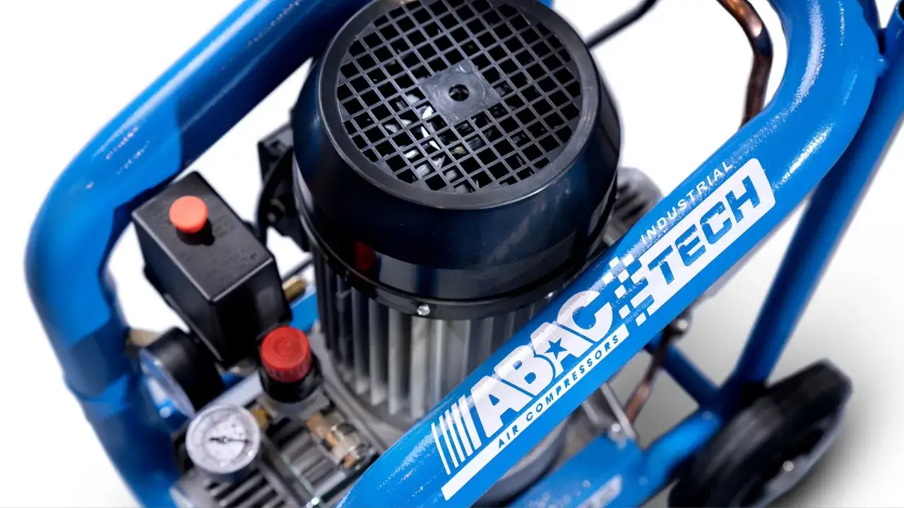 Compresor de aire azul con motor y manómetro. El logo de ABAC AIR COMPRESSORS es visible en el marco.