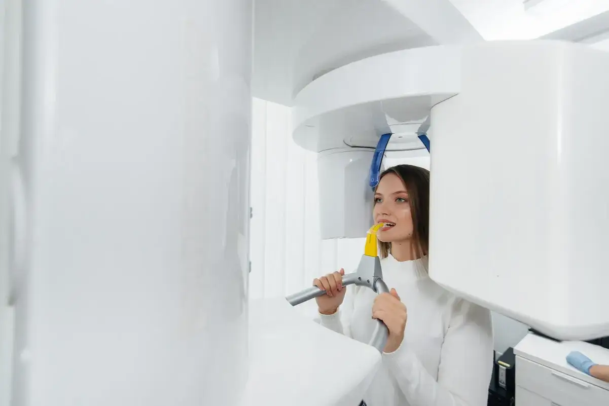 Kobieta w białym swetrze poddaje się badaniu tomografii stożkowej w gabinecie stomatologicznym.