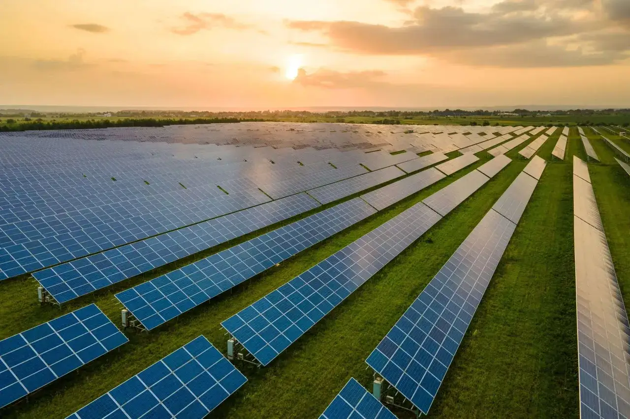 Ogromne pole paneli słonecznych odbija zachodzące słońce, symbolizując czystą energię słoneczną.